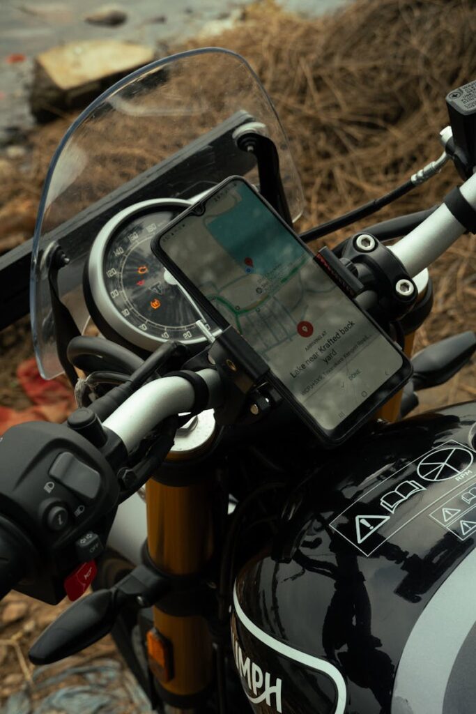 Close-up of a motorcycle handlebar with a smartphone displaying GPS navigation.